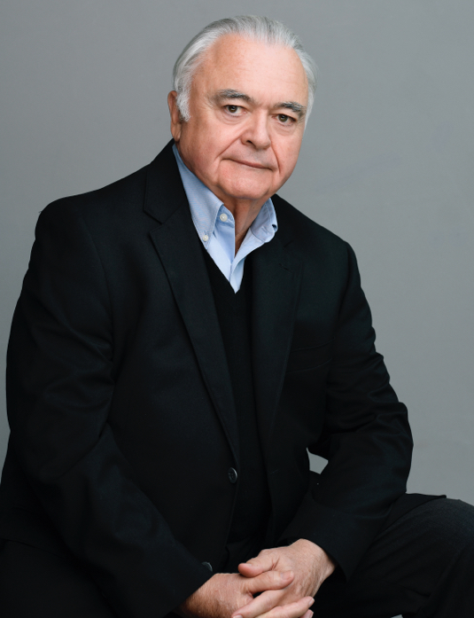 Peter Cleveland sitting on a stool in a black 3-piece suit